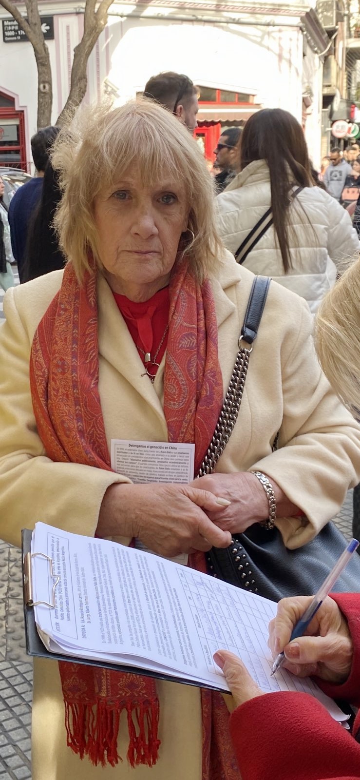 图5~6:(左)一位小女孩在聆听学员讲真相,同时认真阅读手中的大法传单。(右)中国城,一位女士紧握大法传单,她的朋友在呼吁结束中共迫害的请愿书上签名。