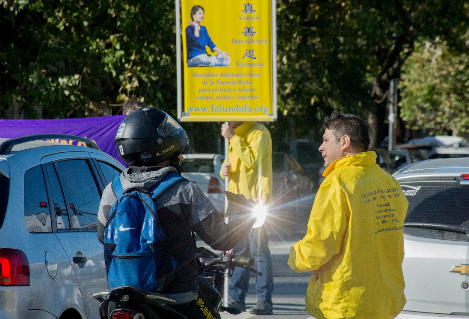 图9:在红绿灯处,学员们站在车辆旁,举着标语和横幅,告诉人们中国正在发生的迫害以及法轮大法的真、善、忍原则。