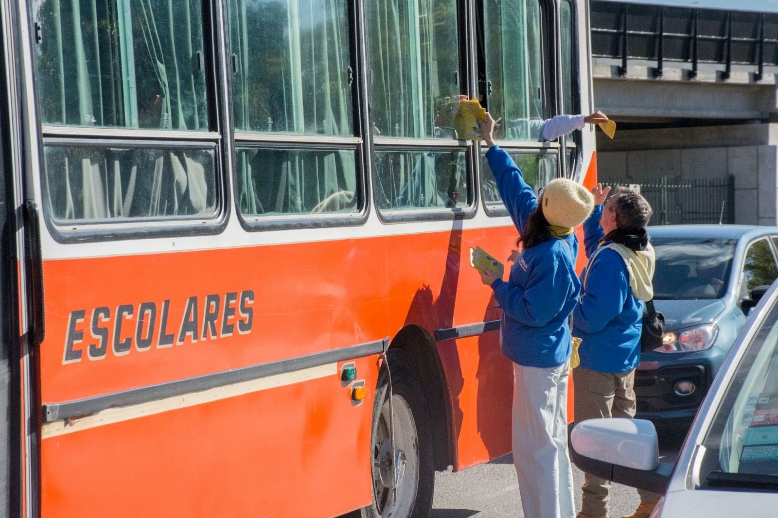 图12:在布宜诺斯艾利斯中共大使馆前,法轮功学员给校车上的学生们发传单。