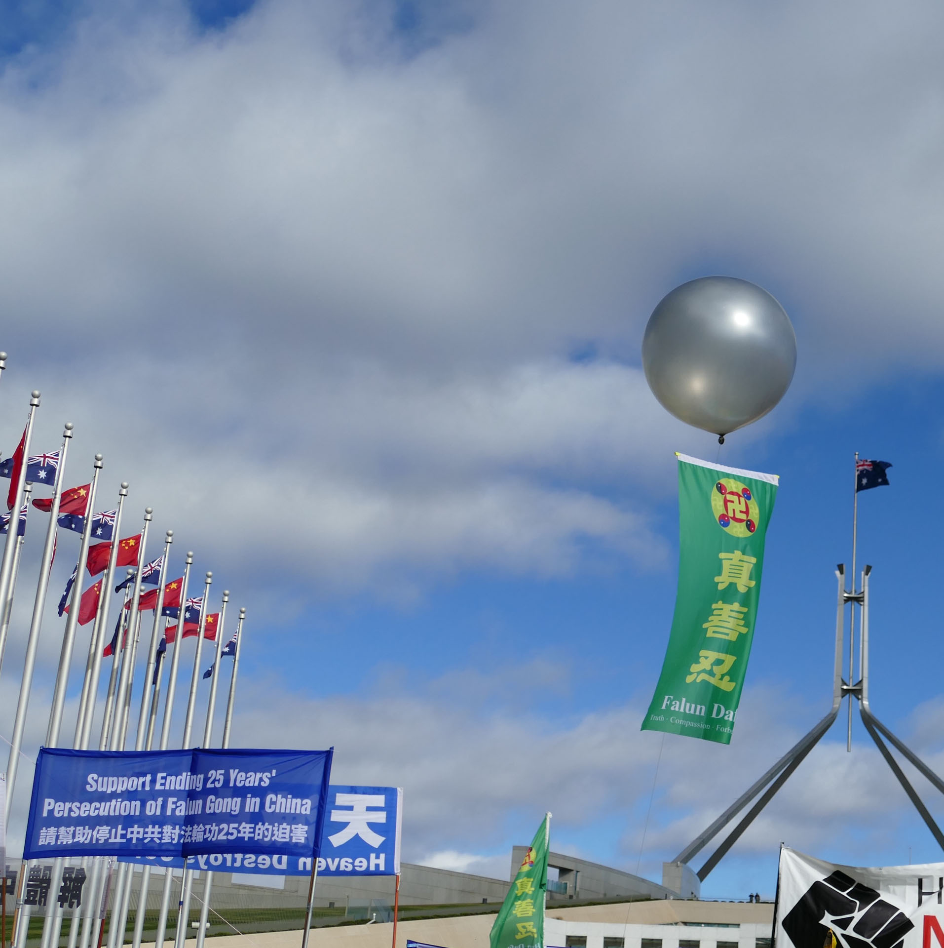 图7:六月十七日,在堪培拉国会大厦前的抗议集会现场上空,飘扬着写有真善忍字样的彩色条幅。