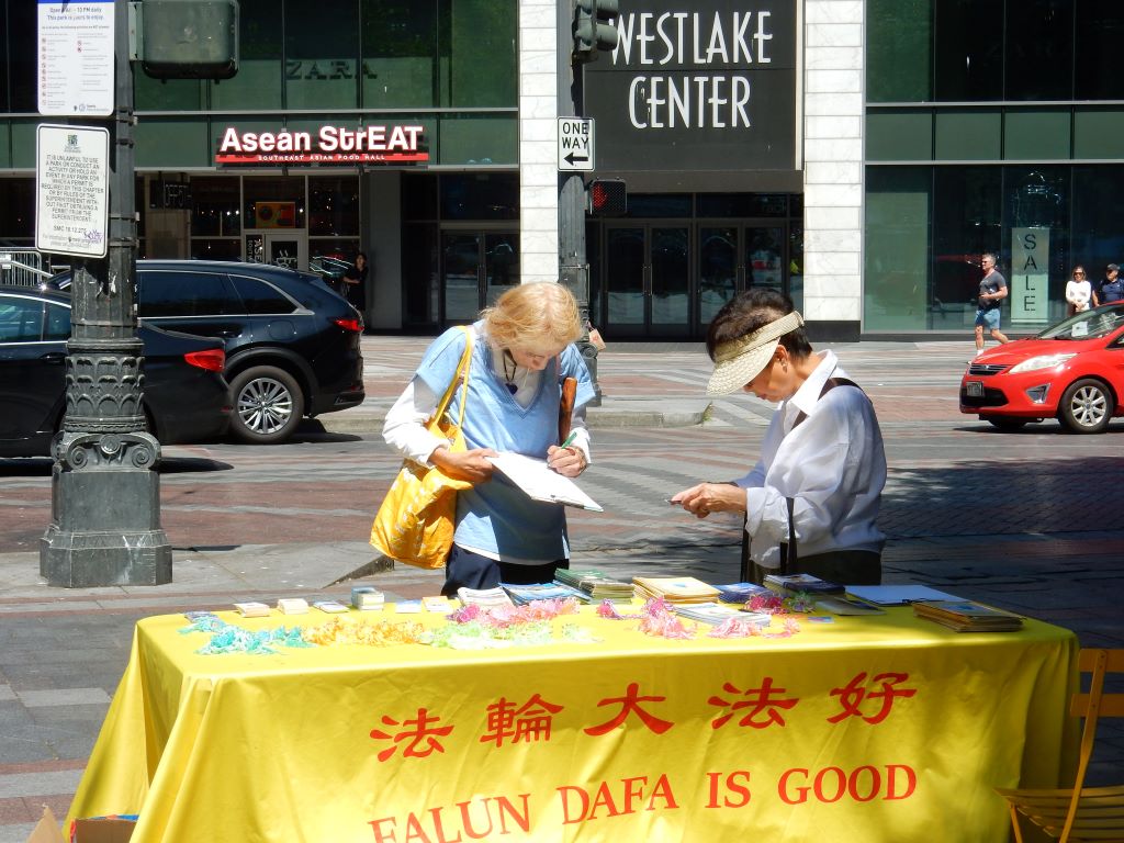 图2:集会上,明白真相的当地人在征签表上签名支持法轮功学员反迫害。