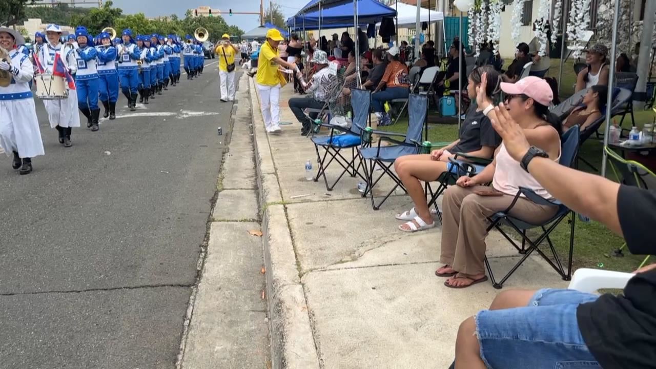 '图3:路边观赏关岛解放八十周年纪念日游行民众接受法轮功学员递送的真相的传单。'