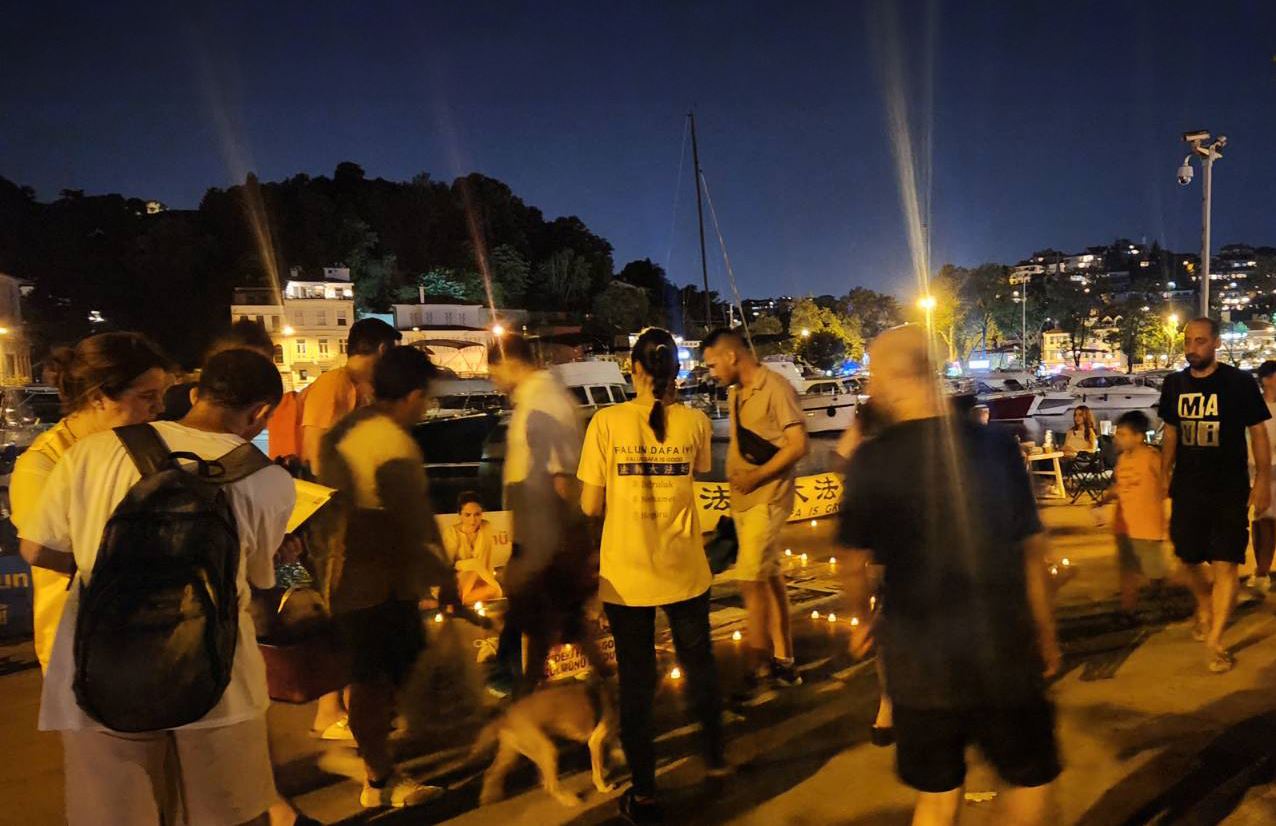 '图4~5:七月二十日晚,学员们再次来到中领馆前,悼念被中共迫害致死的中国法轮功学员。活动现场很多民众前来了解真相,并在结束中共迫害的征签表上签名。'