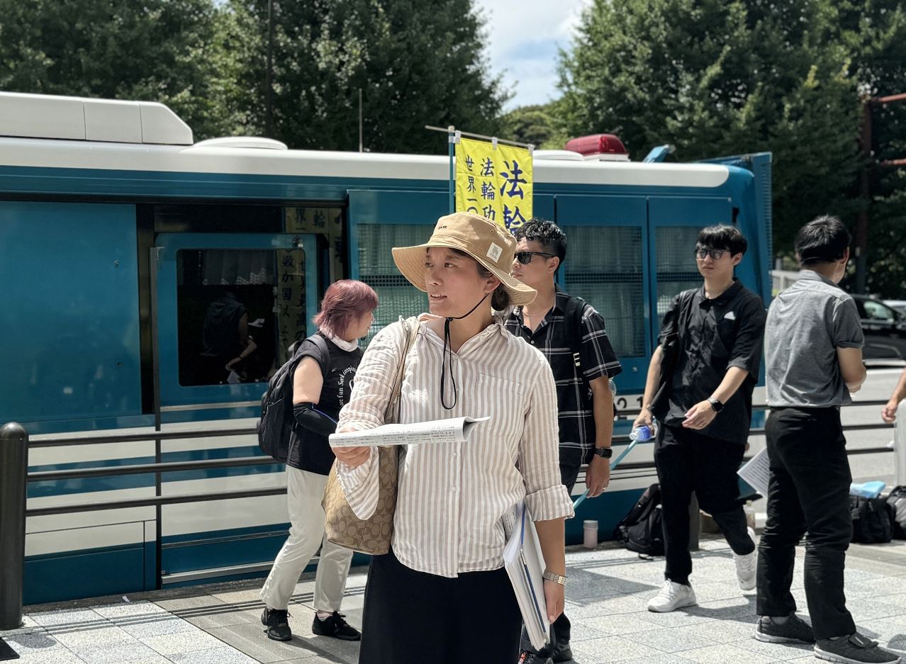 '图4:向过往的行人派发真相资料的法轮功学员刘希月。'