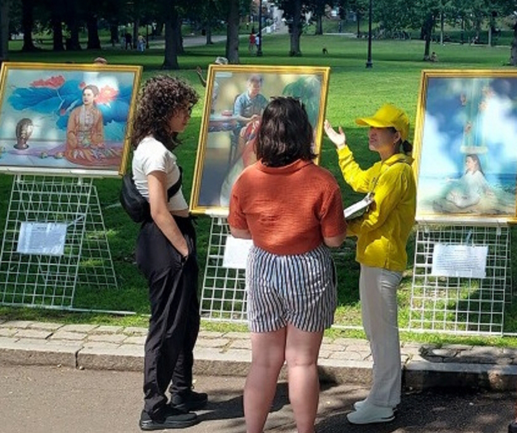 图3:两位女士认真听着解说人员讲解真善忍美展的画作的内涵。