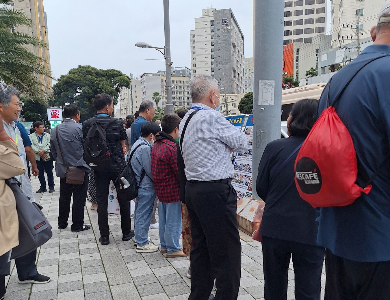 '图1~2:在乐天免税店前,中国游客们驻足阅读法轮功真相展板。'