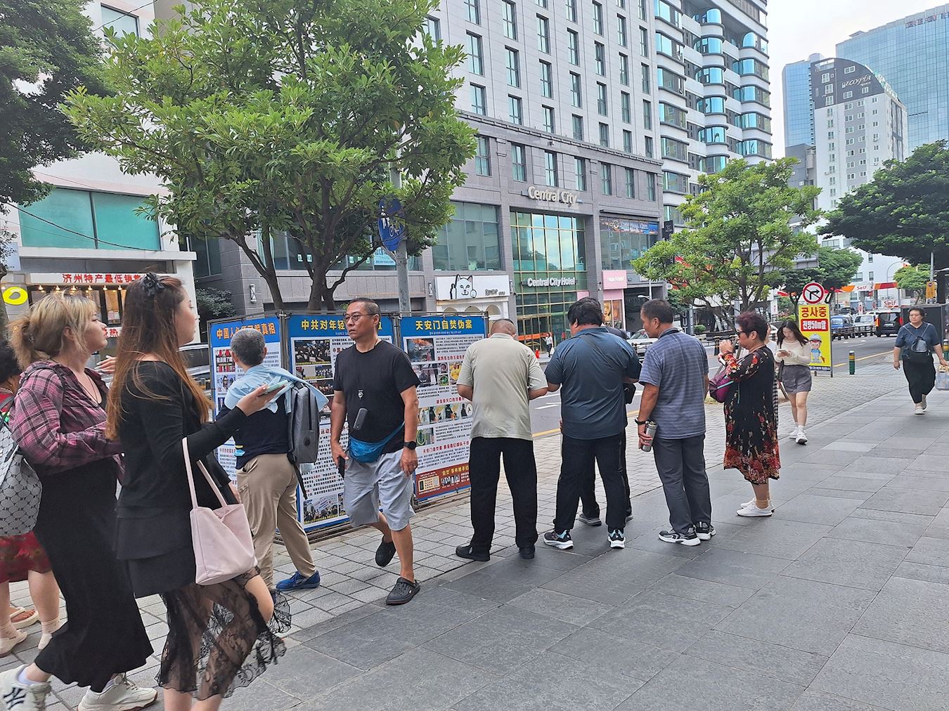 '图3~4:在新罗免税店前,法轮功学员的真相展板,让来往的中国游客有机会了解真相。'