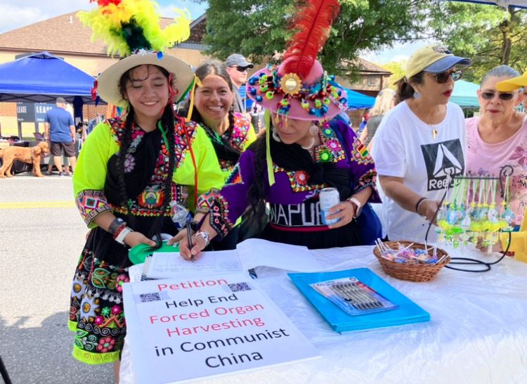 '图7:二零二四年九月二十一日,在马里兰州普尔斯维尔日(Poolesville Day)活动上,民众了解真相后,来到法轮大法展位前,签名抵制中共活摘法轮功器官及其残酷迫害法轮功学员。'