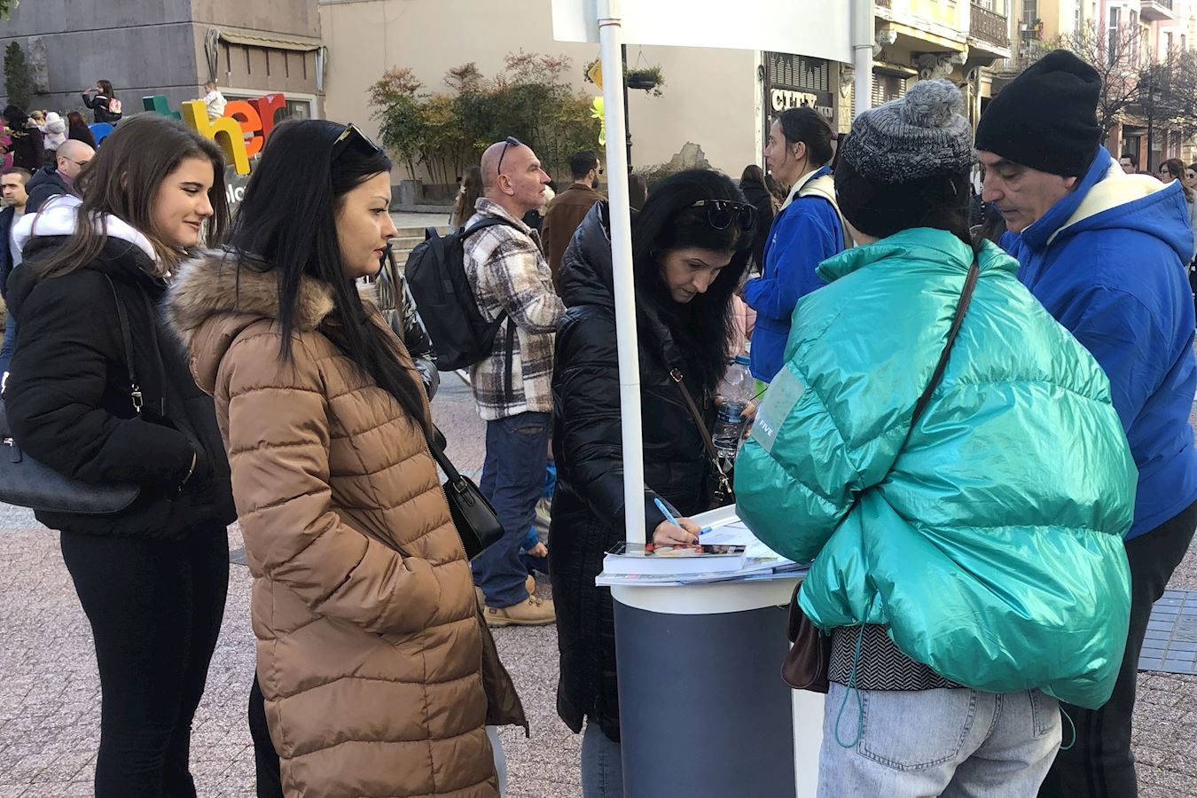 '图13:两位女士对中共迫害感到震惊,在请愿书上签名。'
