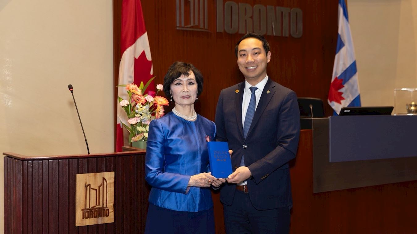'图3:张铁钧(Tia Zhang)女士赠送法轮功著作英文《转法轮》给加拿大国会议员王启荣(Kevin Vuong)'