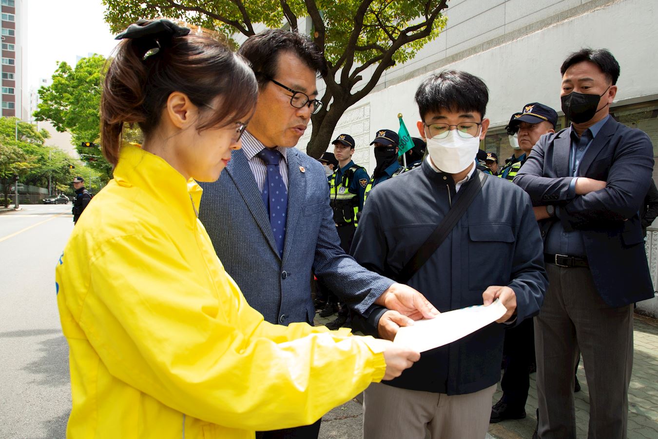 '图6:韩国法轮大法佛学会向釜山总领事馆出入警察传达佛学会声明书。'