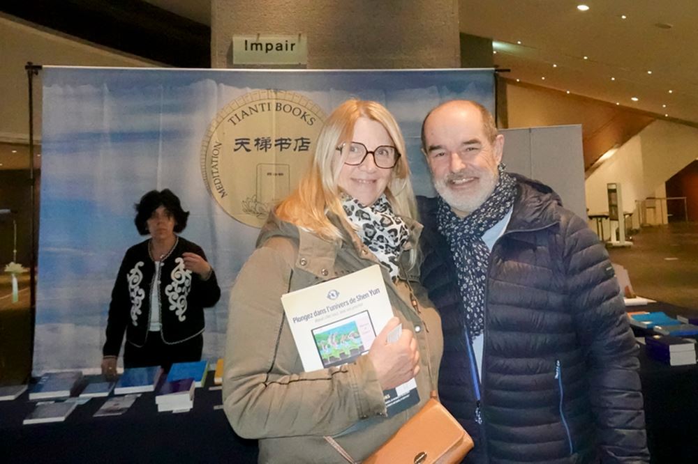 '图7:二零二五年二月十八日晚,市府绿化部的前主任伊夫·盖特(Yves Gaté)与太太安妮·盖特(Annie Gaté)在法国南特市观赏了神韵演出后,在法国天梯书店的展位上购买了法轮大法书籍。(大纪元)'