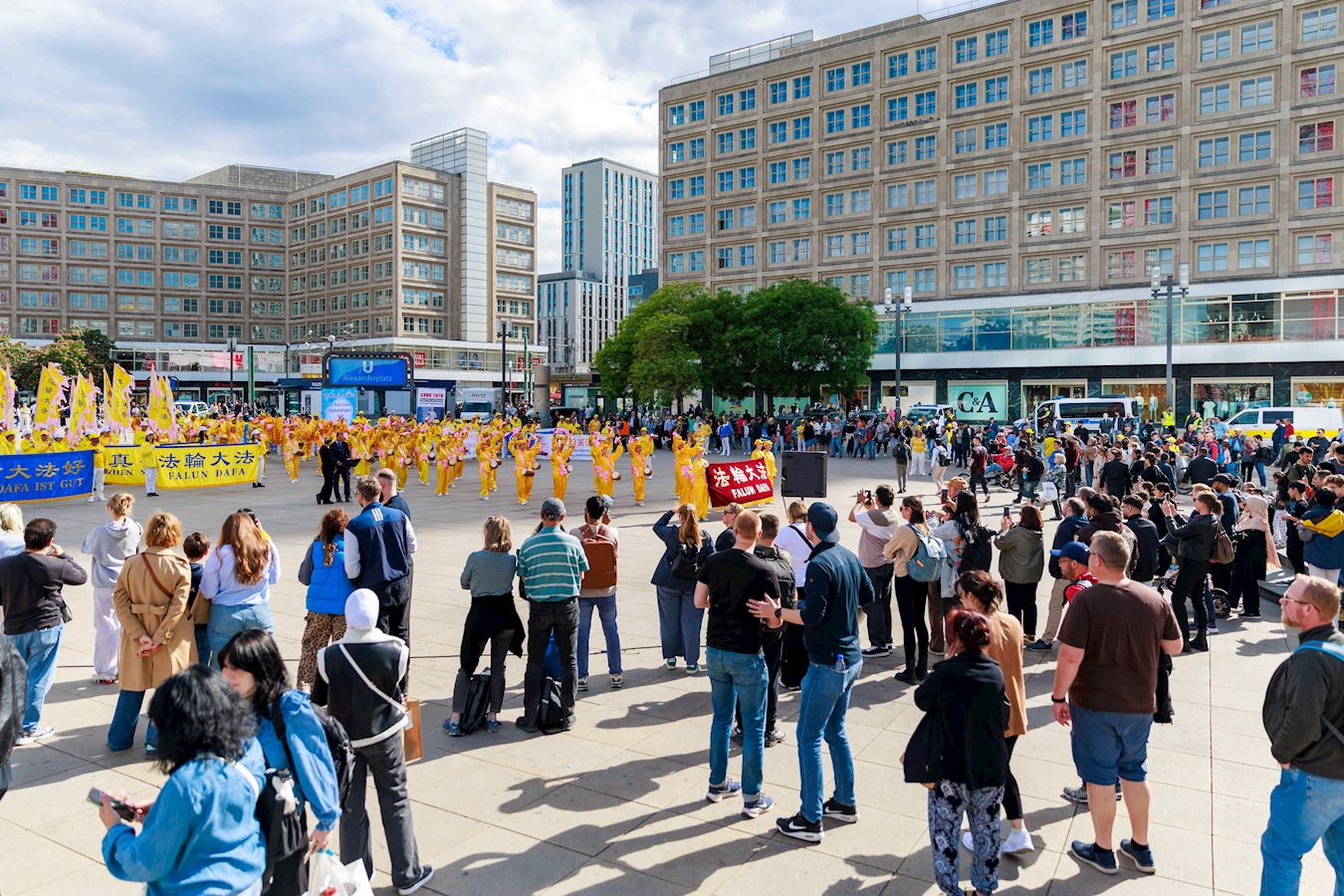 '图11~12:在交通枢纽亚历山大广场(Alexanderplatz)告诉民众法轮大法好,很多路人拿出手机摄影留念'