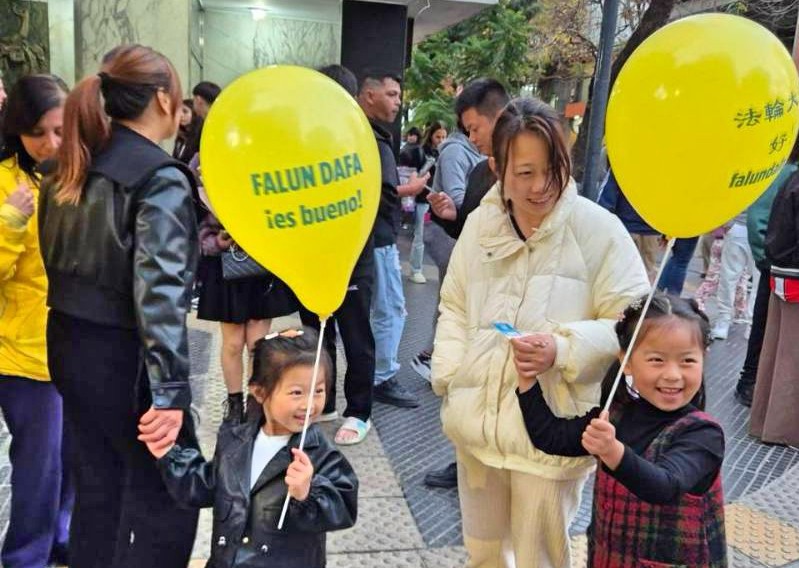 图2~3:法轮功学员将写有“法轮大法好”的黄颜色气球送给孩子们,孩子们非常开心。