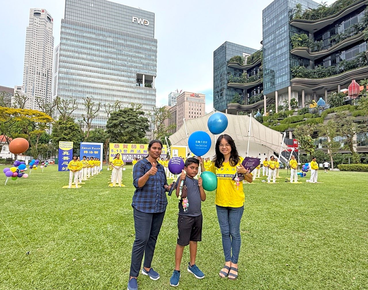 '图4:来自印度的尼兰(左)携十岁儿子与法轮功学员一起庆祝世界法轮大法日,期盼参加接下来的法轮功九天学习班。'