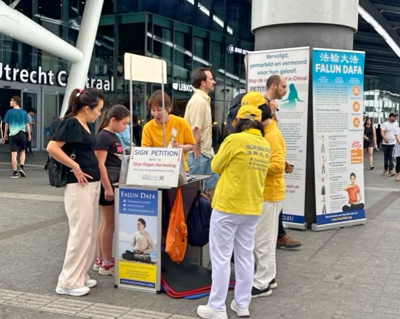 '图1~2:二零二五年六月二十二日,荷兰法轮功学员在乌得勒支(Utrecht)中央火车站附近举办活动,许多经过活动现场的路人来了解真相,并在请愿书上签名。'