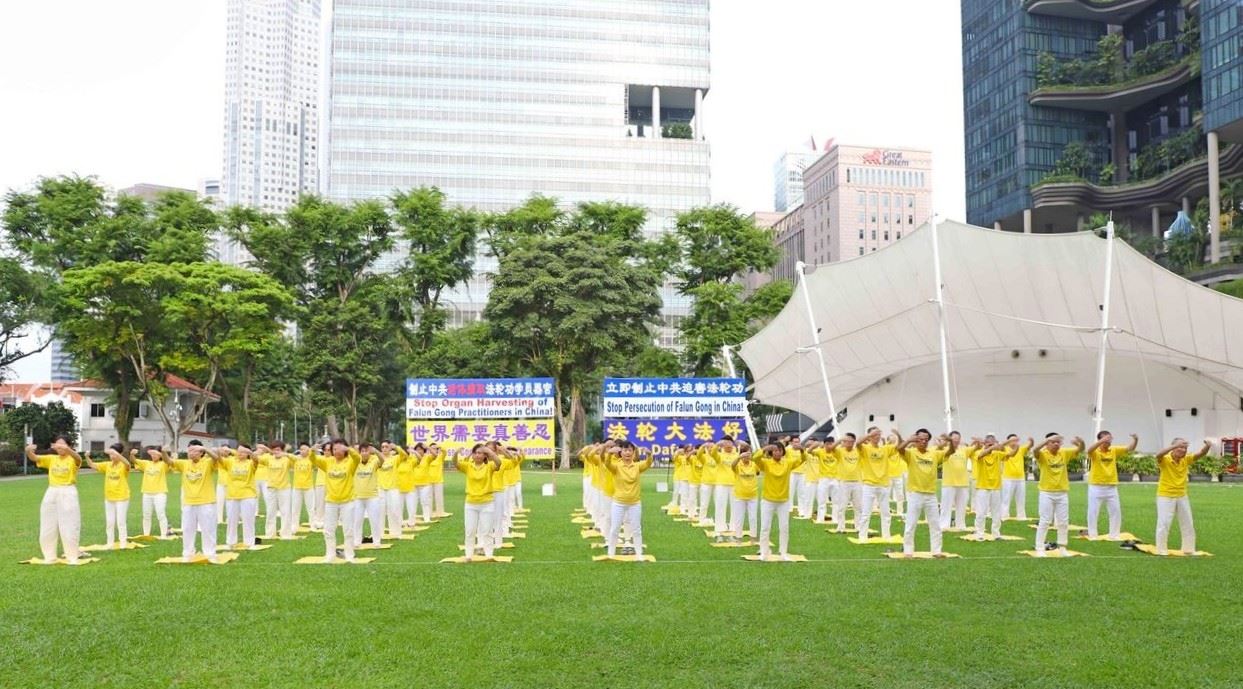 '图1~2:二零二五年七月十五日,新加坡法轮功学员在芳林公园举办反迫害二十六年活动。图为学员们在集体炼功。'