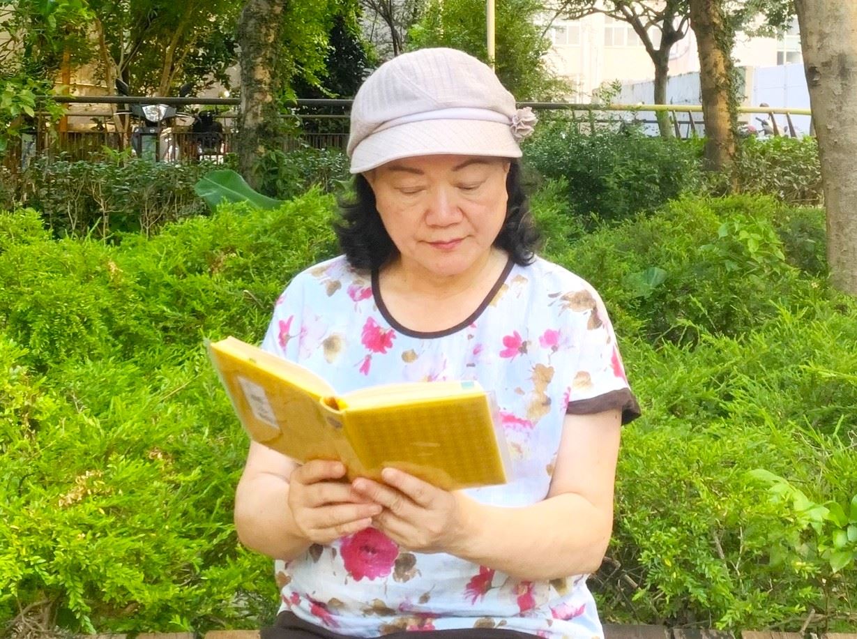 '图1:曼娜在认真拜读《转法轮》,她表示这是一本教人返本归真的天书。'