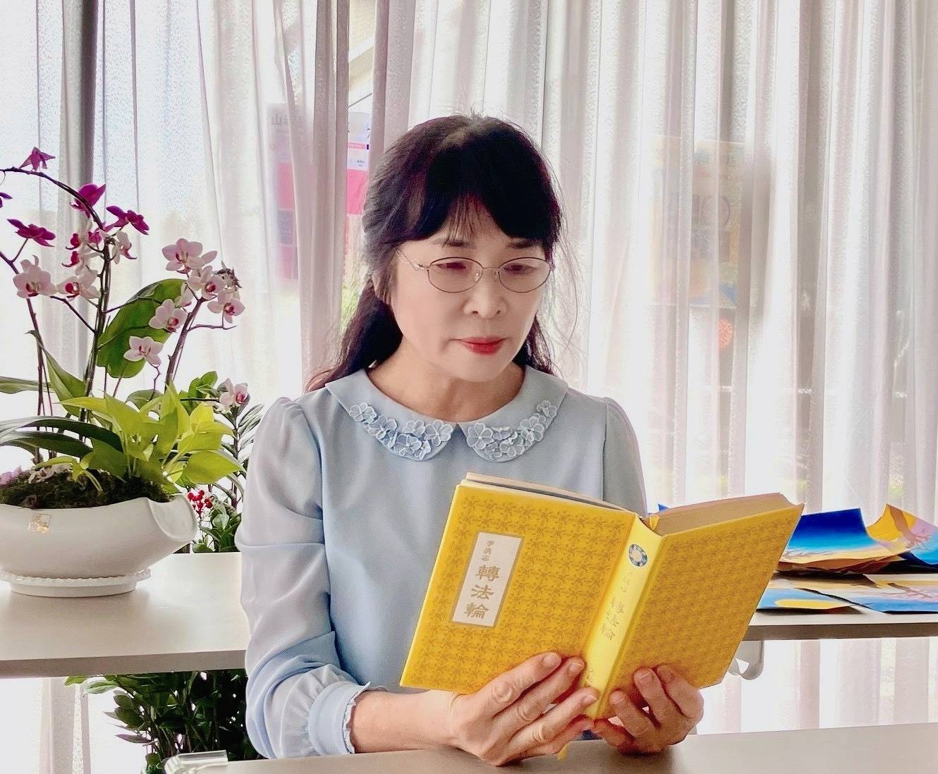 图1:从事三十年小学教育的林月蕊在阅读法轮大法著作-《转法轮》