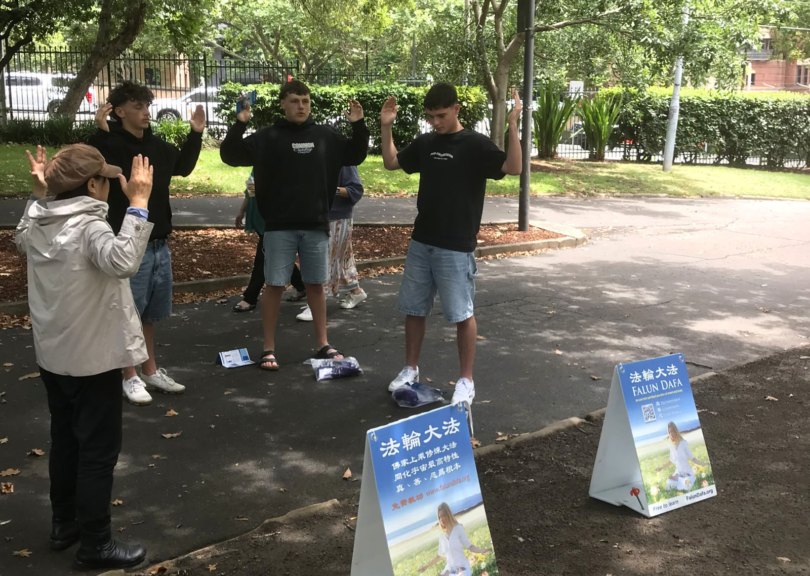 图6:三位中学生正在跟随学员学炼法轮功。。